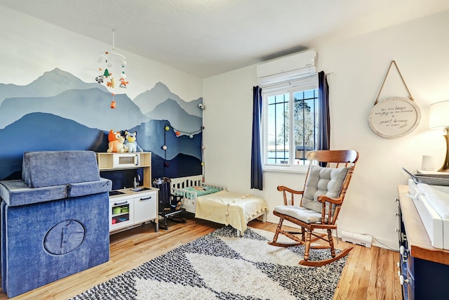 sitting room with hardwood / wood-style floors and an AC wall unit