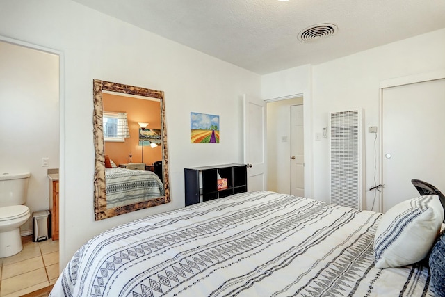 tiled bedroom featuring connected bathroom and a textured ceiling