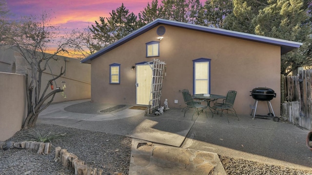 back house at dusk featuring a patio