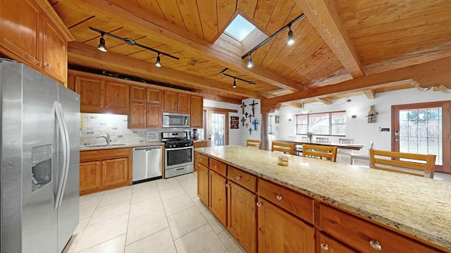 kitchen with appliances with stainless steel finishes, plenty of natural light, and wooden ceiling