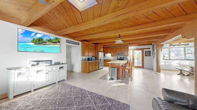 living room featuring beamed ceiling, a skylight, light tile patterned floors, and wooden ceiling