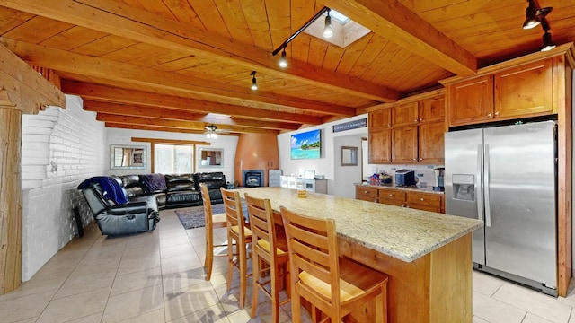 kitchen with light stone counters, stainless steel fridge, wooden ceiling, and light tile patterned flooring