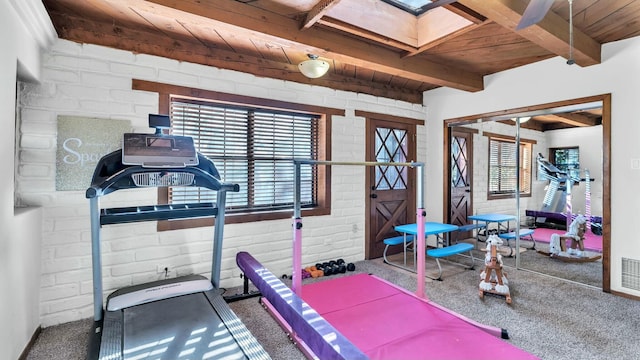 exercise room with brick wall, carpet, wooden ceiling, and a skylight