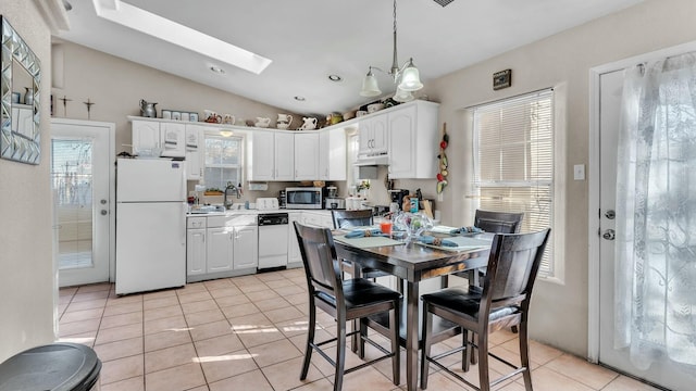 kitchen with pendant lighting, light tile patterned floors, white appliances, white cabinetry, and vaulted ceiling with skylight