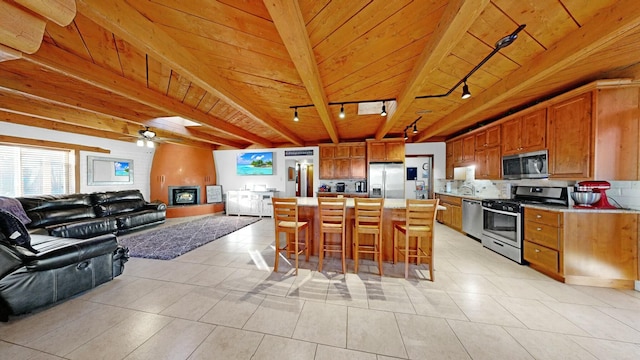 kitchen with a kitchen bar, wood ceiling, appliances with stainless steel finishes, a kitchen island, and decorative backsplash