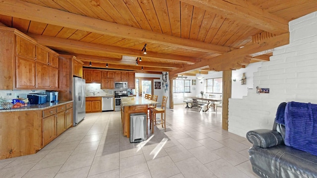 kitchen with light stone counters, a kitchen bar, stainless steel appliances, and a kitchen island