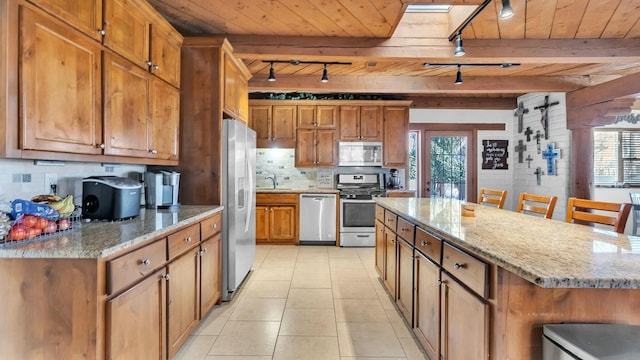 kitchen with light stone counters, stainless steel appliances, a skylight, and a breakfast bar area