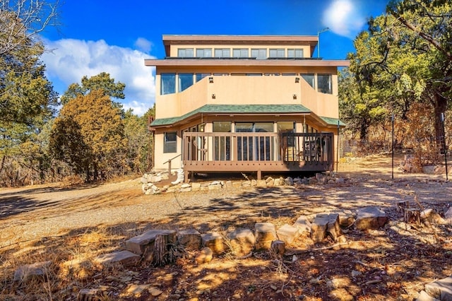 back of property with a sunroom and stucco siding