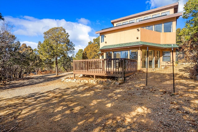 rear view of house featuring a deck and stucco siding