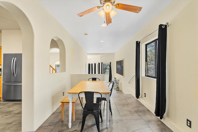 dining space with a ceiling fan and arched walkways