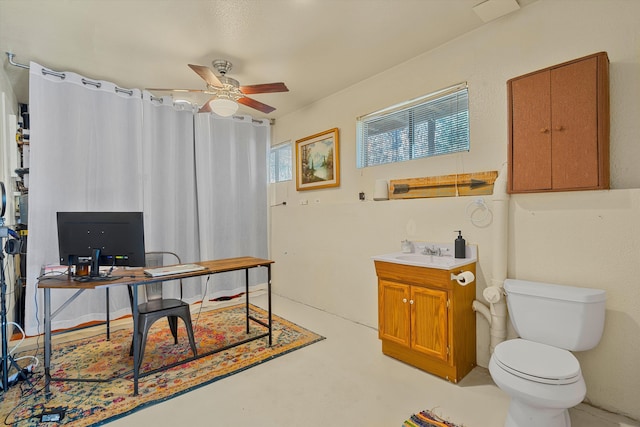 home office with finished concrete flooring, ceiling fan, and a sink