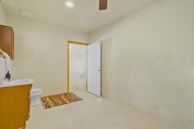 bathroom featuring toilet, vanity, and a ceiling fan