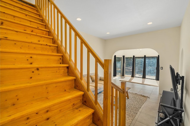 stairway with tile patterned flooring, arched walkways, and recessed lighting