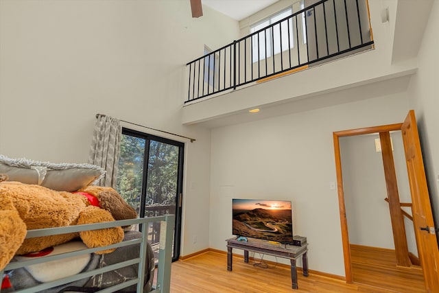 bedroom with baseboards, a towering ceiling, and light wood finished floors