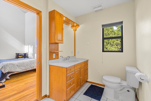 bathroom featuring toilet, ensuite bathroom, vanity, baseboards, and tile patterned floors