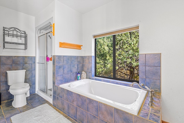 bathroom with toilet, a garden tub, tile walls, and a stall shower