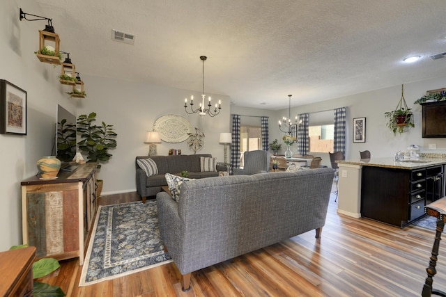 living room featuring a notable chandelier, a textured ceiling, and light wood-type flooring