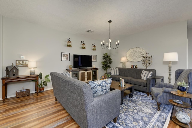 living room featuring an inviting chandelier, hardwood / wood-style floors, and a textured ceiling