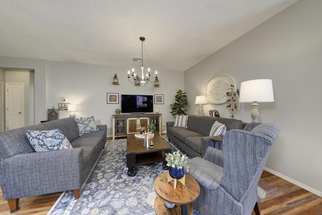 living room with lofted ceiling, a textured ceiling, dark wood-type flooring, and a chandelier