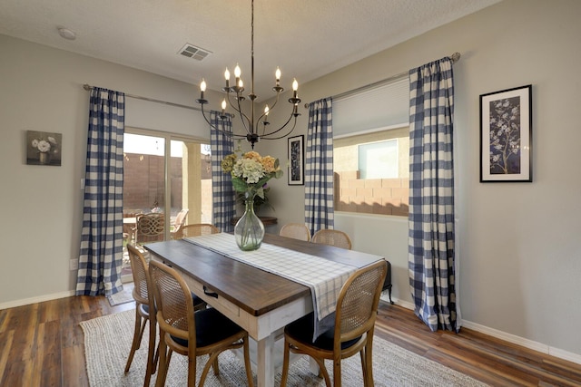 dining room featuring dark hardwood / wood-style floors, a chandelier, and a textured ceiling