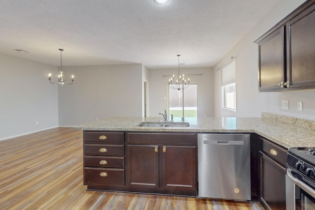 kitchen featuring light wood finished floors, appliances with stainless steel finishes, dark brown cabinetry, a sink, and an inviting chandelier