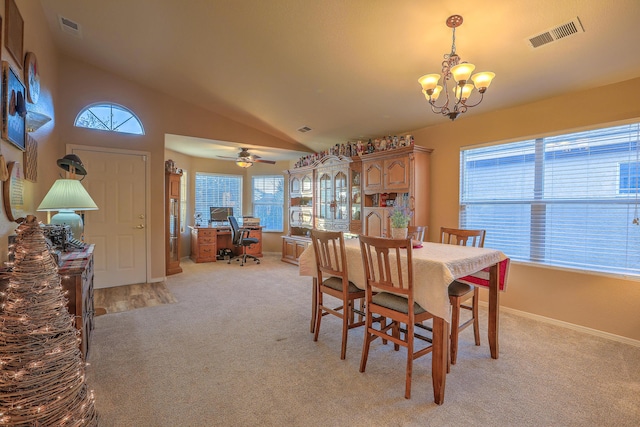 dining area with vaulted ceiling, ceiling fan with notable chandelier, and light carpet