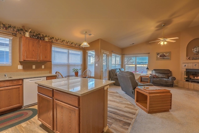 kitchen featuring a center island, vaulted ceiling, white dishwasher, pendant lighting, and a tiled fireplace