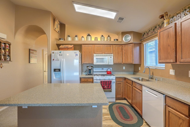 kitchen with light stone counters, white appliances, sink, and light hardwood / wood-style flooring