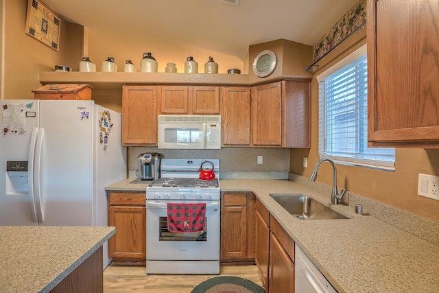 kitchen with light stone counters, sink, white appliances, and light wood-type flooring