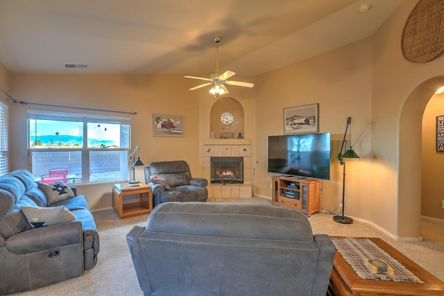 carpeted living room with ceiling fan, lofted ceiling, and a tile fireplace