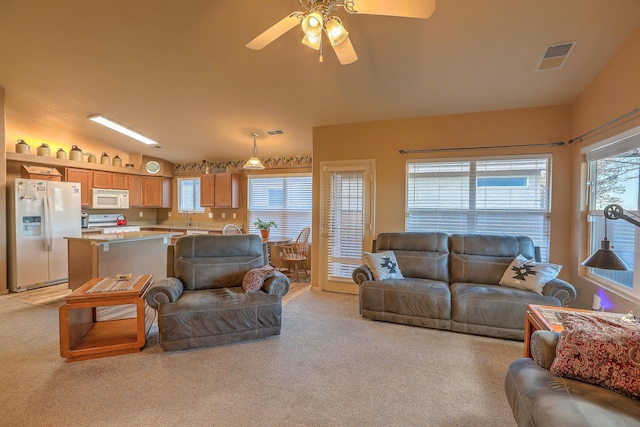 carpeted living room with plenty of natural light, ceiling fan, and vaulted ceiling