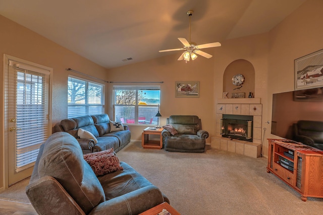 living room with a tiled fireplace, light colored carpet, ceiling fan, and lofted ceiling