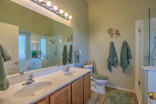 bathroom with vanity, hardwood / wood-style flooring, a shower with door, and toilet