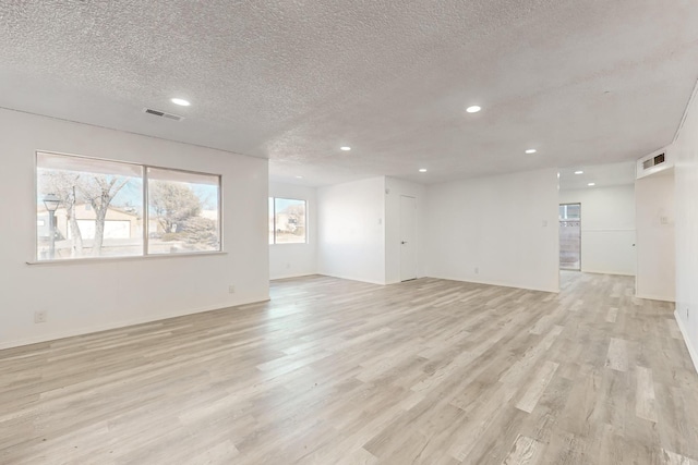 unfurnished room featuring a textured ceiling and light wood-type flooring