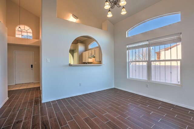 unfurnished room featuring a high ceiling and an inviting chandelier