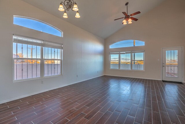 empty room featuring ceiling fan with notable chandelier, a wealth of natural light, and high vaulted ceiling