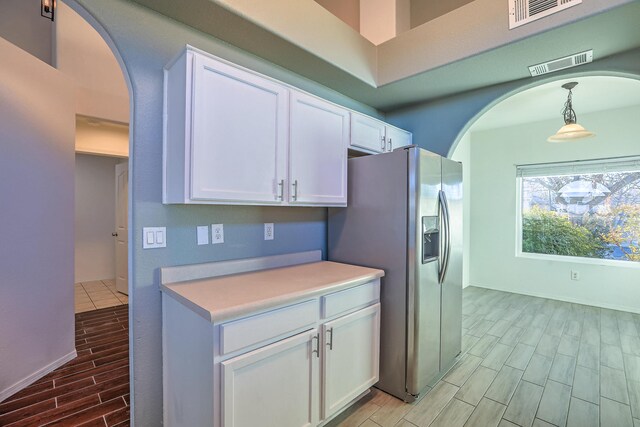 kitchen with decorative light fixtures, stainless steel fridge with ice dispenser, and white cabinets