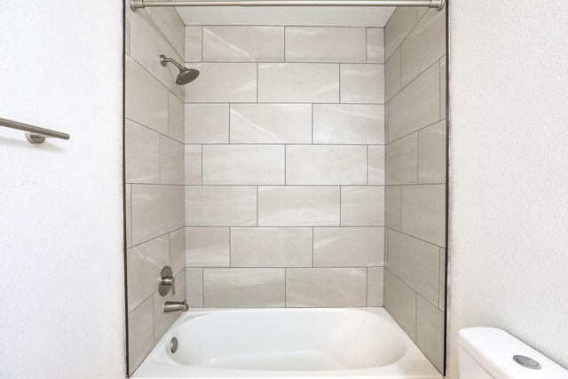 bathroom with tiled shower / bath combo and toilet