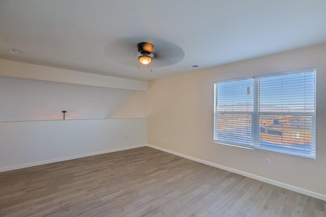 empty room featuring lofted ceiling with beams, ceiling fan, and light wood-type flooring