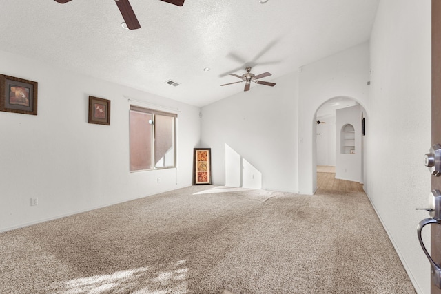 unfurnished room featuring ceiling fan, carpet flooring, vaulted ceiling, and a textured ceiling