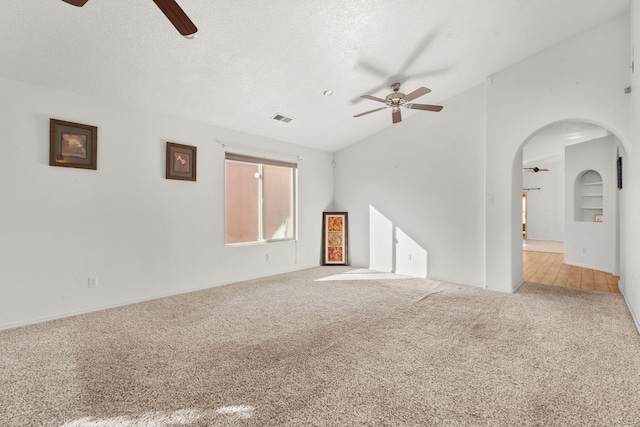 carpeted spare room with lofted ceiling, ceiling fan, built in shelves, and a textured ceiling