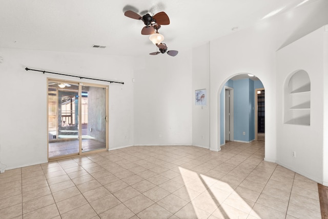 empty room with light tile patterned floors, lofted ceiling, a ceiling fan, and built in features