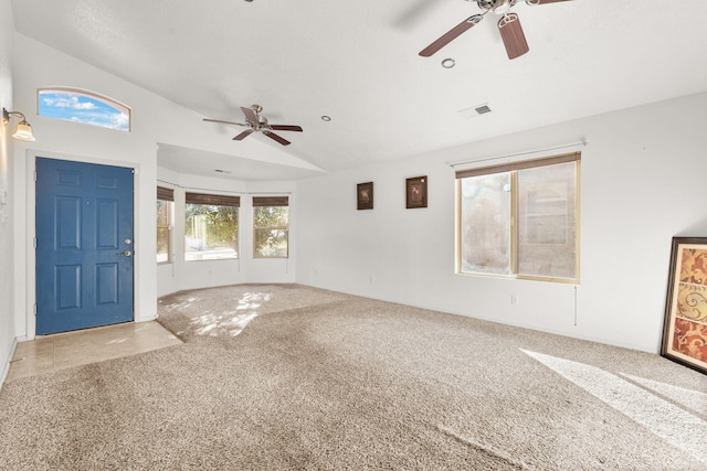 foyer featuring lofted ceiling, ceiling fan, carpet, and visible vents