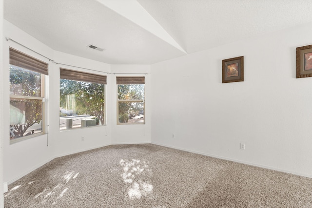 spare room with a textured ceiling, vaulted ceiling, visible vents, and baseboards