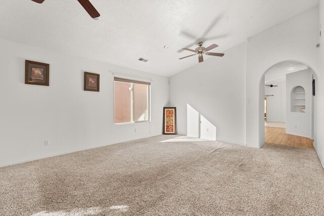 unfurnished living room featuring visible vents, light carpet, vaulted ceiling, ceiling fan, and a textured ceiling