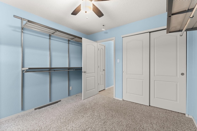 unfurnished bedroom featuring light colored carpet, a closet, and ceiling fan