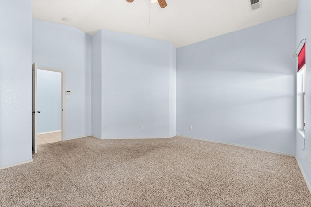 empty room featuring vaulted ceiling, a ceiling fan, visible vents, and light colored carpet