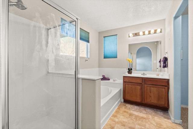 bathroom featuring shower with separate bathtub, vanity, and a textured ceiling