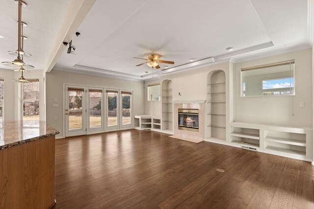 unfurnished living room featuring a tray ceiling, dark wood-type flooring, and a high end fireplace