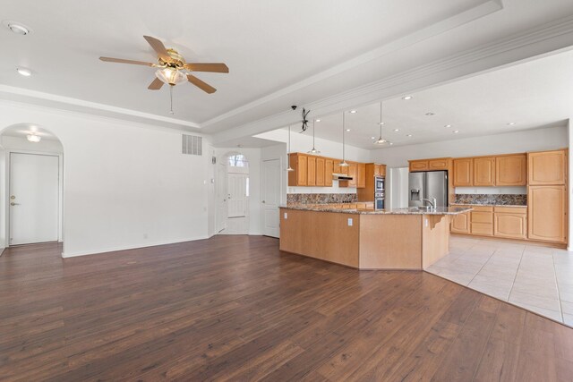 kitchen featuring light wood finished floors, a raised ceiling, visible vents, open floor plan, and stainless steel fridge